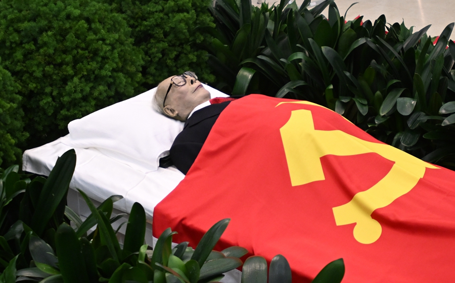 江泽民同志的遗体安卧在鲜花翠柏丛中，身上覆盖着鲜红的中国共产党党旗